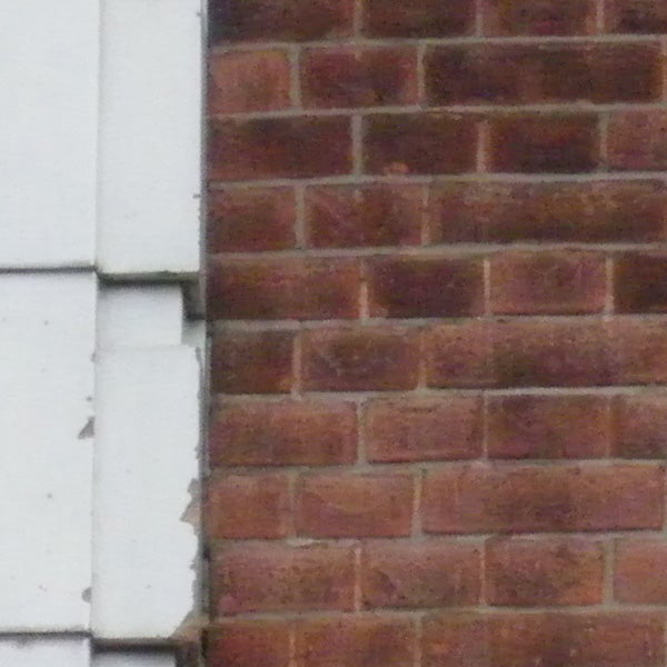 Low-resolution photo of a brick wall and sidingimage of a brick wall with white siding.