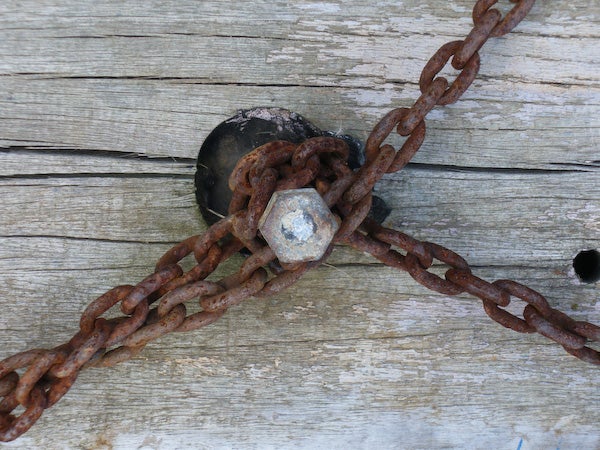 Rusty chain and bolt on weathered wooden planks.