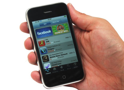Hand holding an Apple iPhone 3G displaying Facebook app.