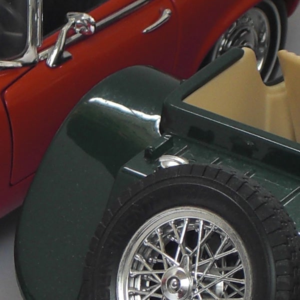 Close-up of two model cars, red and green, showing fine detail.Close-up of vintage toy cars.