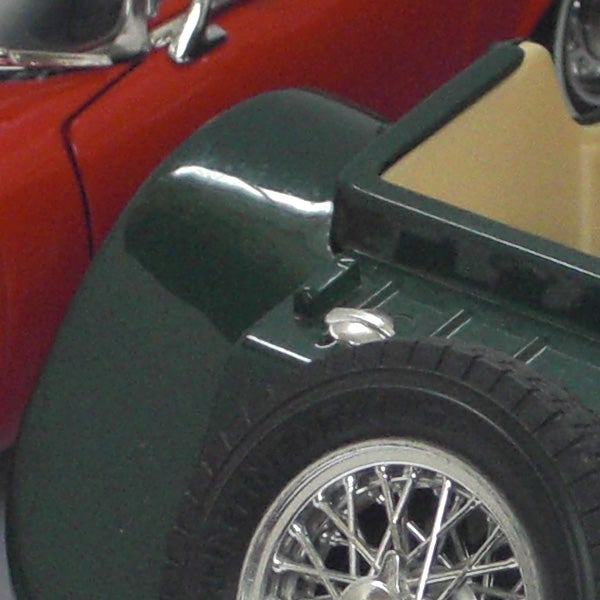 Close-up of a vintage car's wheel and fender.Cropped image of a classic green and red car.