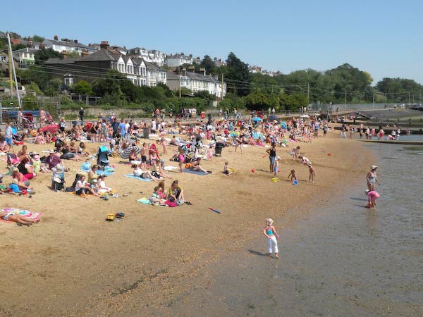 Crowded beach scene with people enjoying sunny weather.Crowded beach scene with people sunbathing and playing.