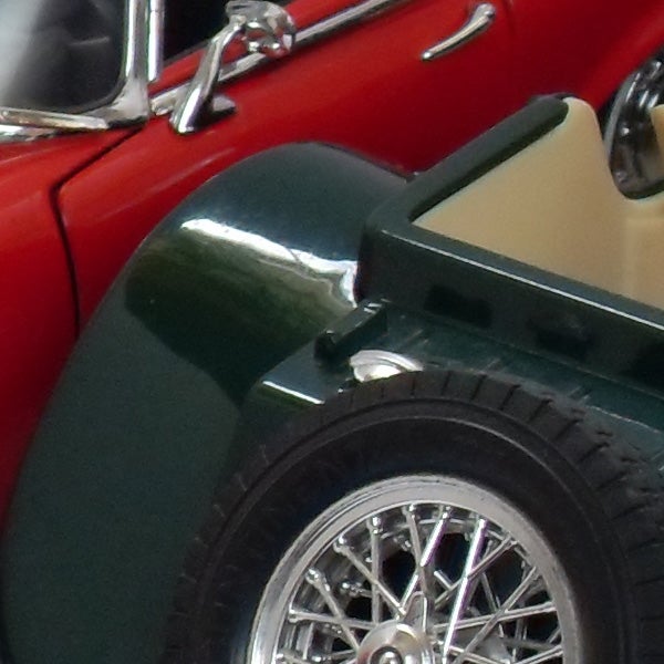 Close-up of miniature vintage car model wheels and fender.Close-up of red vintage car model with detailed wheels.