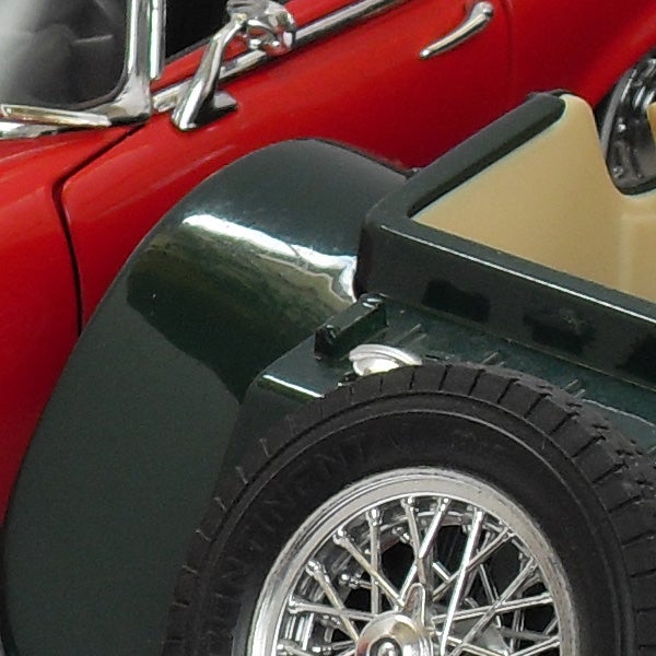 Close-up of a red vintage car model wheel and detailsClose-up of a vintage red car and black tire.