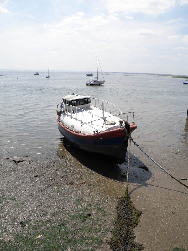 Beached boat on shore with other boats in distanceBoat moored on shore, clear details with sky and sea background.