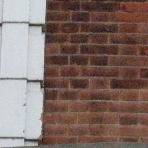 photo of a brick wall, possibly low light condition.Low-resolution photo of a brick wall with noise.