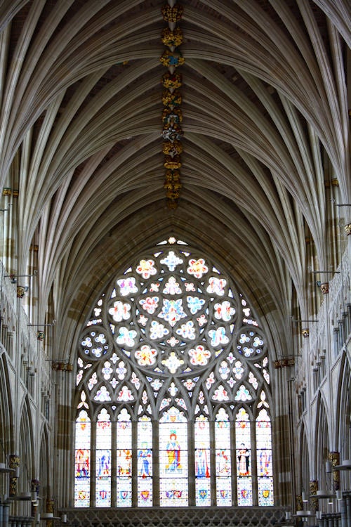 Gothic cathedral interior with stained glass window.Photograph of a cathedral's vaulted ceiling and stained glass window.