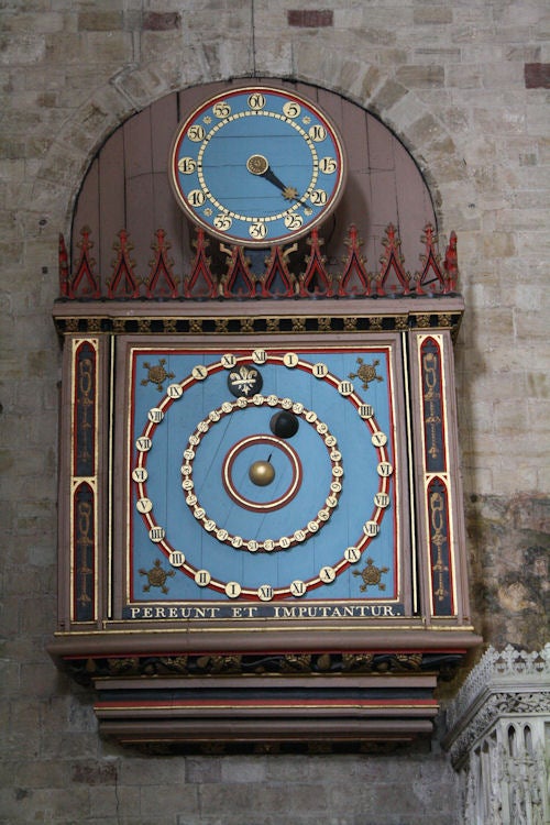 Ornate antique astronomical clock on a stone wall.Ornate astronomical clock on cathedral wall.