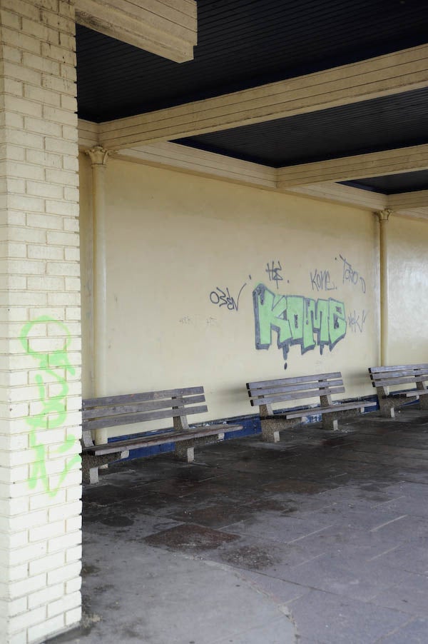 Graffiti on wall at a bus stop with empty benchesGraffiti on wall at a train station platform with benches.