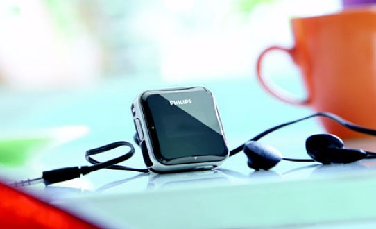 Philips GoGear SA2840/02 MP3 player with earbuds on table.Philips GoGear SA2840/02 MP3 player with earphones on table.