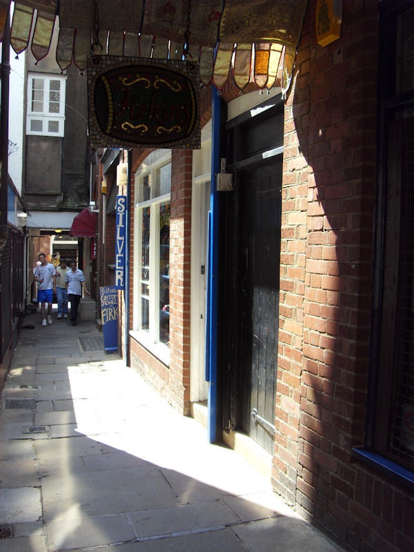 Narrow alleyway with shops and hanging signs in daylight.Narrow alley with shops and hanging signs in daylight.