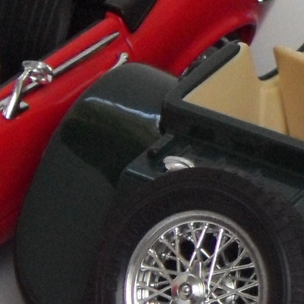 Close-up of a red and black toy car wheel and interior.Close-up of a red toy convertible car wheel and side detail.