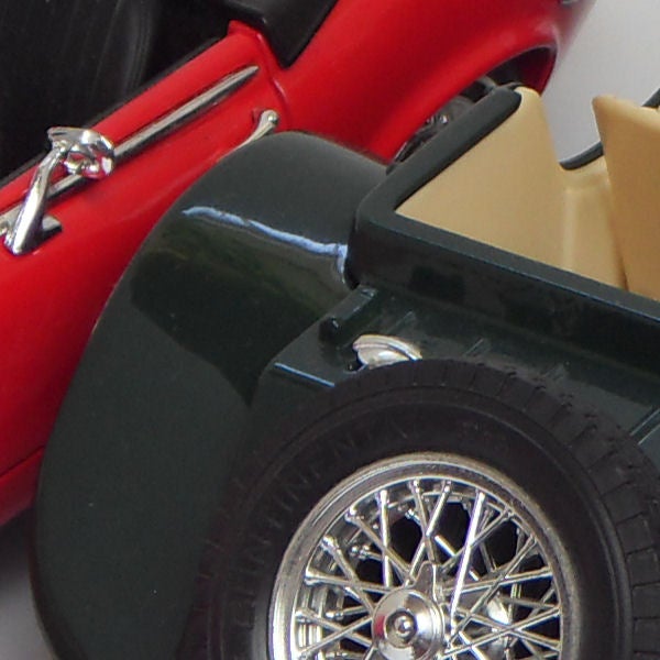 Close-up of a red and black model car with detailed wheels.Close-up of toy cars colliding, showcasing models and details.