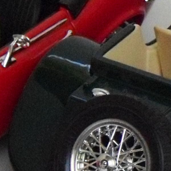 Close-up of a red vintage car's rear side and wheel.Close-up of a red sports car model wheel and side detail