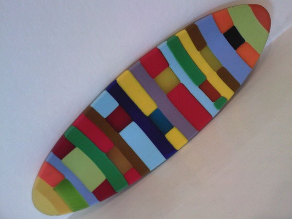 Multicolored striped surfboard on a white background.Colorful surfboard-shaped object with abstract design