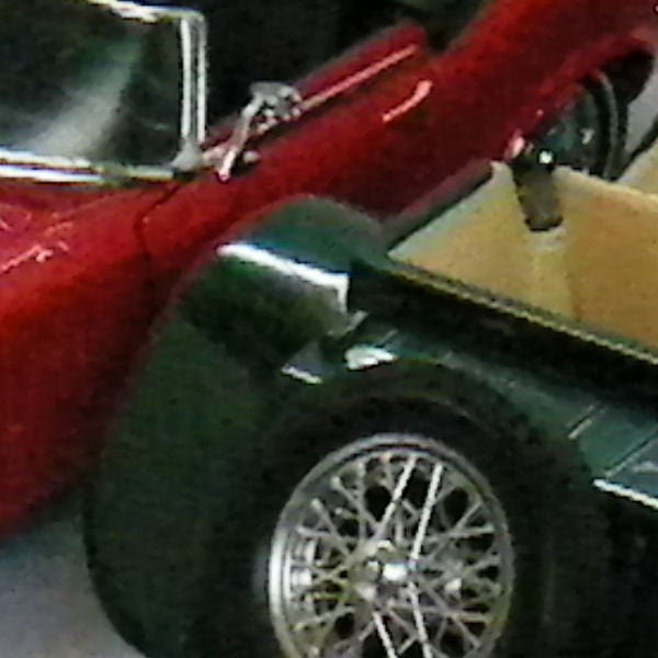 image of two toy cars side by side.Red and green toy cars on a display shelf.