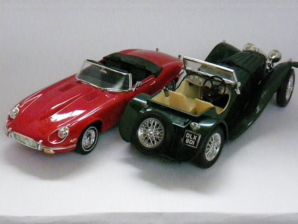 Photo of red and green model cars on a grey surface.Red and green vintage model cars on display