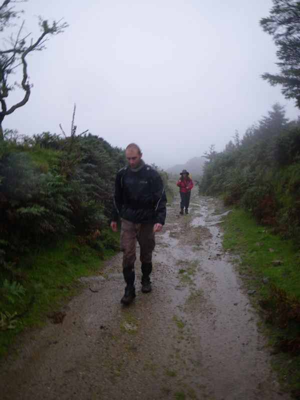 Photo taken with Pentax Optio W60 in rainy, misty outdoor conditions.Two hikers walking on a foggy, wet trail.