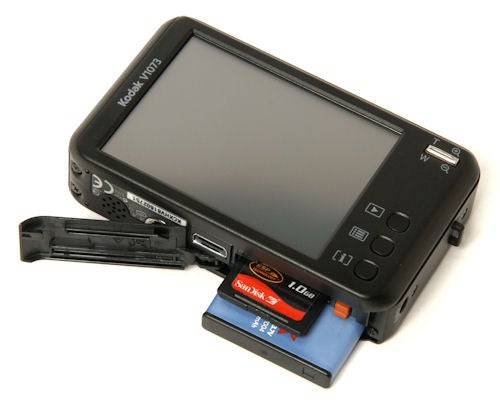 Kodak V1073 camera with open battery compartment showing SD card.Kodak V1073 digital camera with open battery compartment.