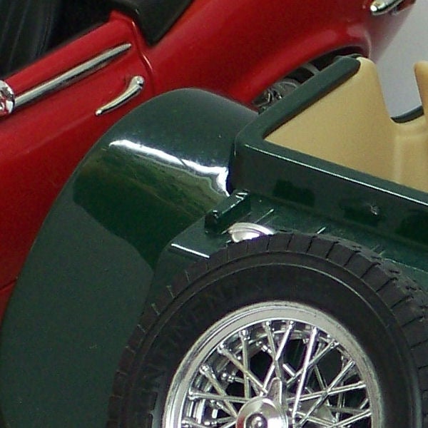 Close-up of a classic red and green model car wheel and fender.