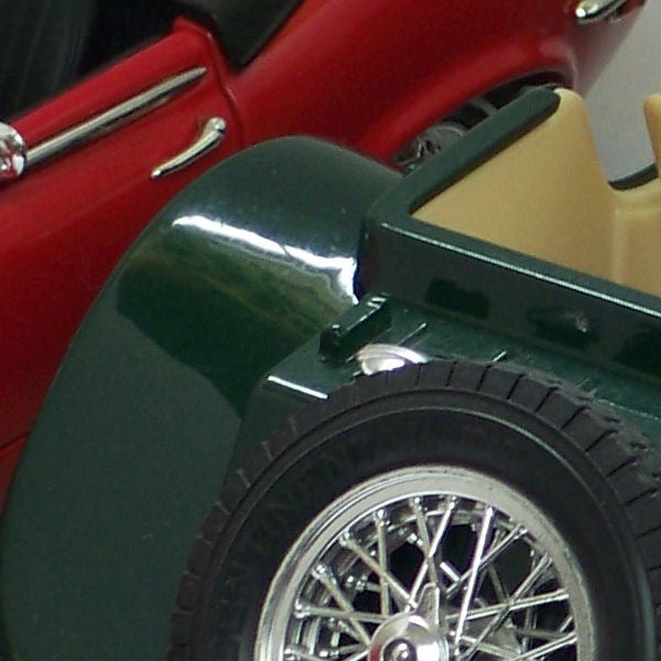 Close-up of a vintage car model wheel and fender.Close-up of classic model cars in red and green.