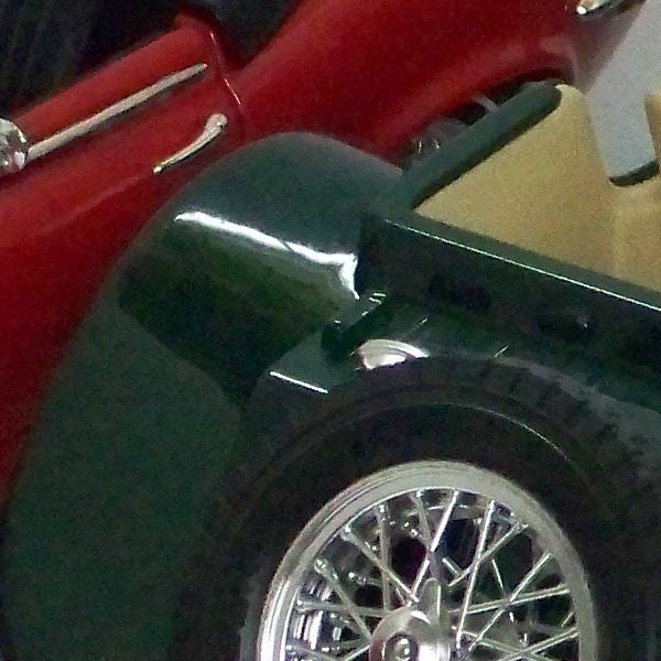 Close-up of a classic car's shiny green fender and wheel.Close-up of a vintage car's wheel and fender.