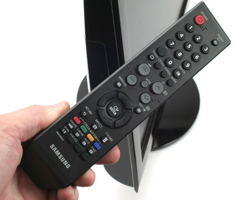 Hand holding Samsung SyncMaster monitor remote control.
