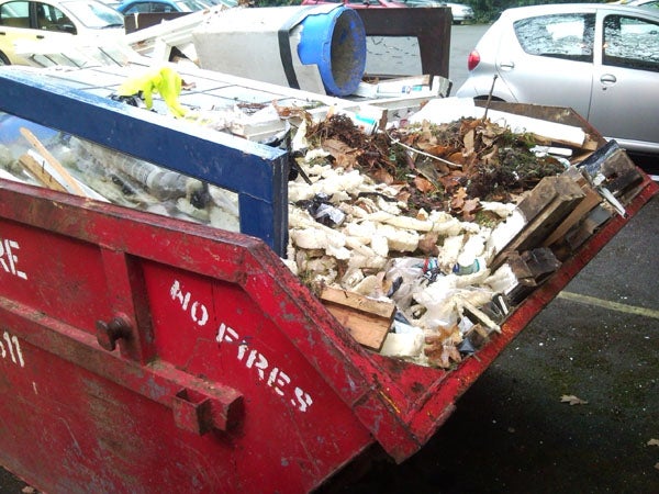 Overfilled construction dumpster with various debris.Overfilled red dumpster with mixed waste and debris.