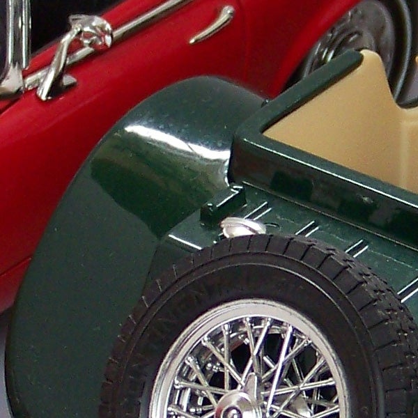 Close-up of a red vintage car model wheel and fender.Close-up of a classic red and green model car wheel and fender.