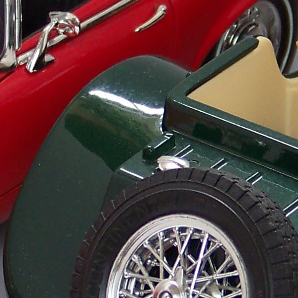 Close-up of a classic red and green model car wheel and fender.Close-up of a red and green vintage toy car wheel and fender.