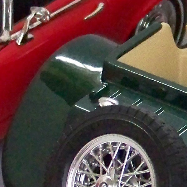 Close-up of vintage red and green cars with chrome detailsVintage red and green cars on display at an exhibition