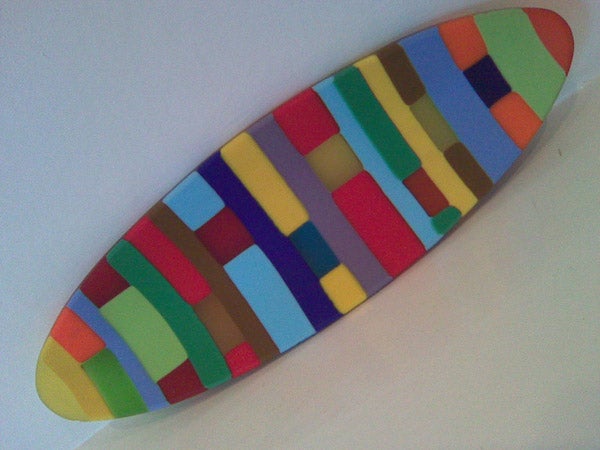 Colorful geometric patterns on a surfboard-shaped objectColorful patterned surfboard on white background.