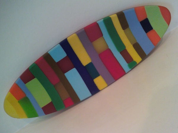 Colorful surfboard-shaped object with mosaic pattern.Colorful abstract patterned surfboard on a white background.