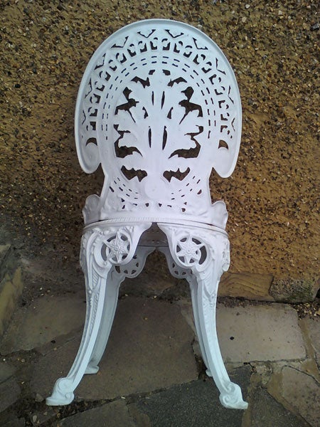White ornate plastic chair against a wall.