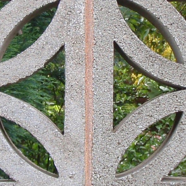 Close-up of a textured metallic surface with circular patterns.Decorative metalwork with foliage in the background.