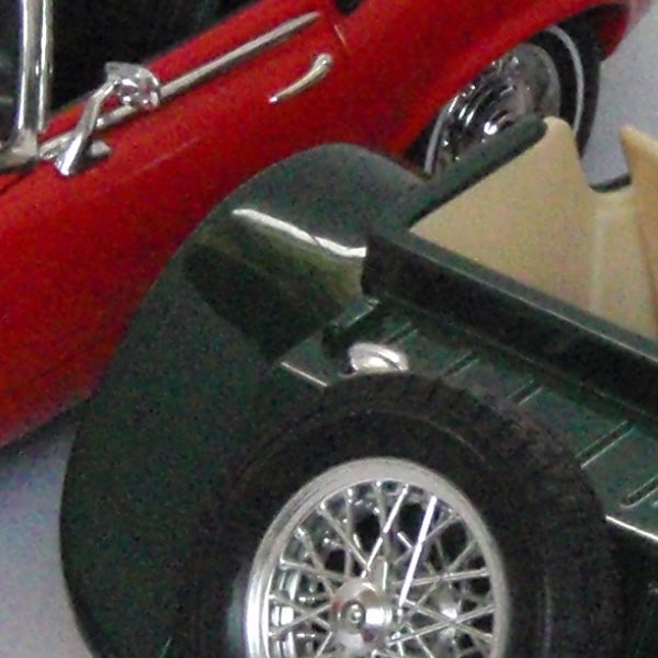 Close-up photo of a green and red toy car.Close-up of miniature red and green vintage cars.