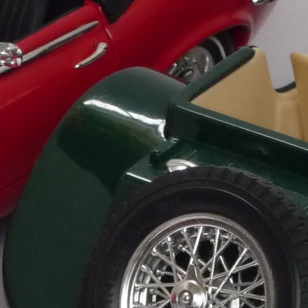 Close-up of classic model cars with detailed wheels and bodywork.Close-up of vintage toy cars with focus on green car wheel.