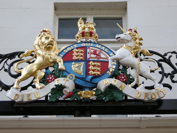 Ornate royal coat of arms with lion and unicorn.Ornate royal crest with lion and unicorn against a building.