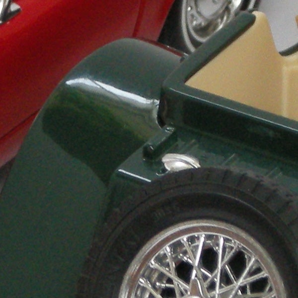 Close-up of a green toy car wheel and fenderClose-up of vintage car model wheel and fender.