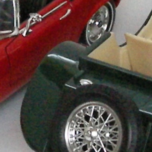 Close-up of toy car wheels with another car in backgroundClose-up of vintage toy cars with selective focus