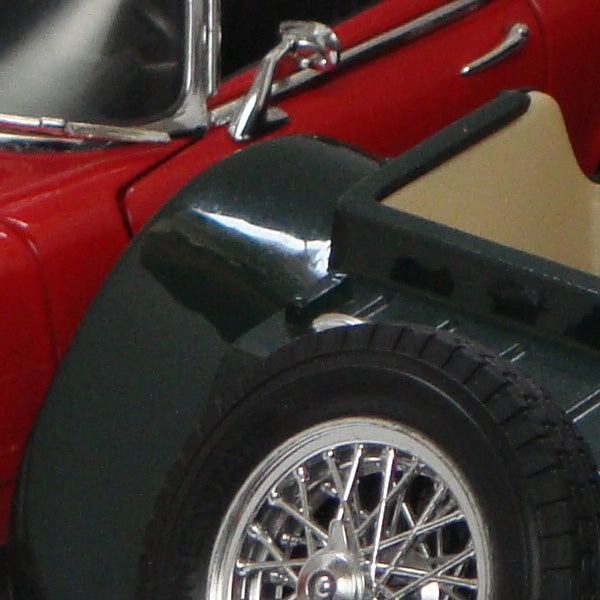Close-up of a red vintage car model wheel and sideClose-up of a red vintage car model's front wheel and fender.