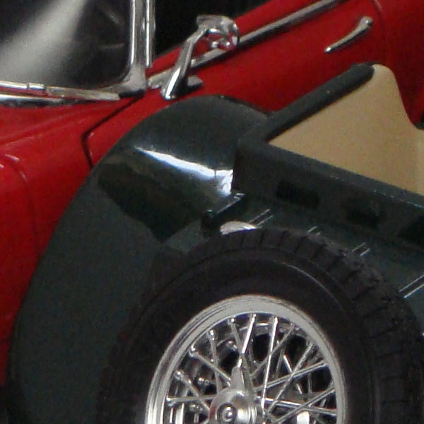 Close-up of a red toy convertible car's wheel and side door.Close-up of a red toy convertible car's side and wheel.
