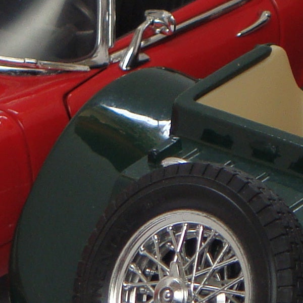 Close-up of a red vintage car model side and wheel.Close-up of a red vintage car's wheel and fender.