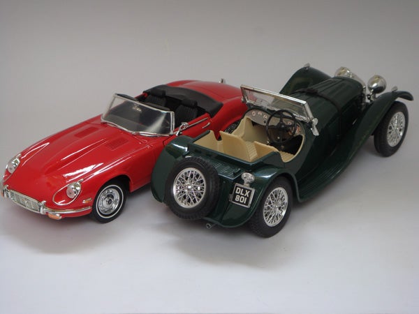 Photo of two model cars, red and green, captured in studio setting.Two miniature model cars displayed side by side.