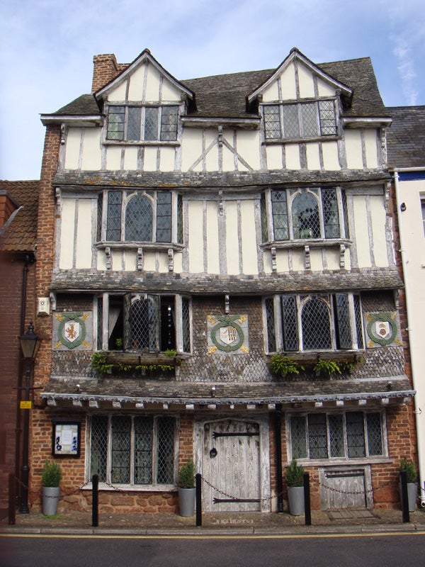 Photo of a historic Tudor-style building taken with a camera.Historic half-timbered building with decorative windows.