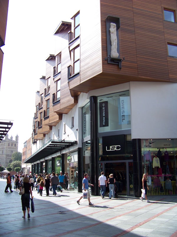 Urban street scene with pedestrians and modern shopsA bustling street scene with shops captured in daylight