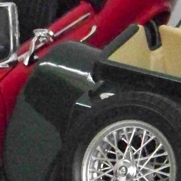 Close-up photo of a classic red car's side mirror and wheel.Close-up of a red vintage car's side and chrome wheel.