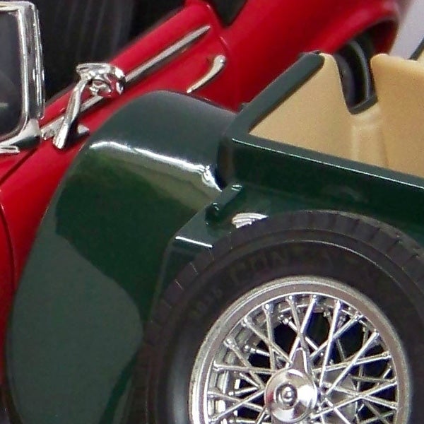 Close-up of a classic car model's wheel and fenderClose-up of a red and green vintage toy car model.