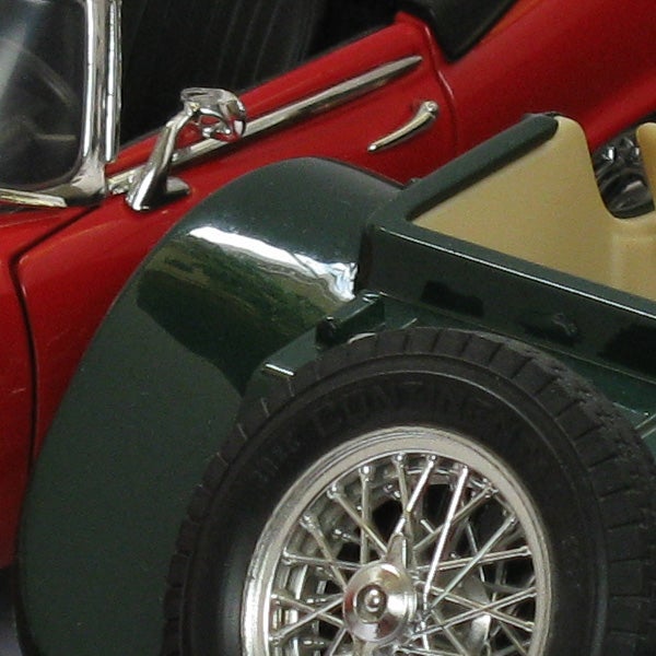 Close-up of a classic red and green model car wheel and fender.Close-up of a vintage red and green toy car's wheel and details.