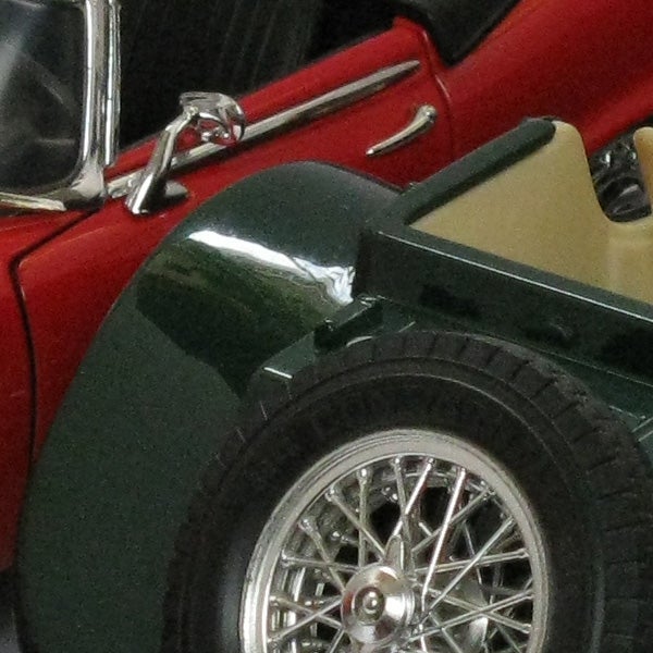 Close-up of a green and red vintage toy car model.Close-up of a toy car wheel and side mirror.
